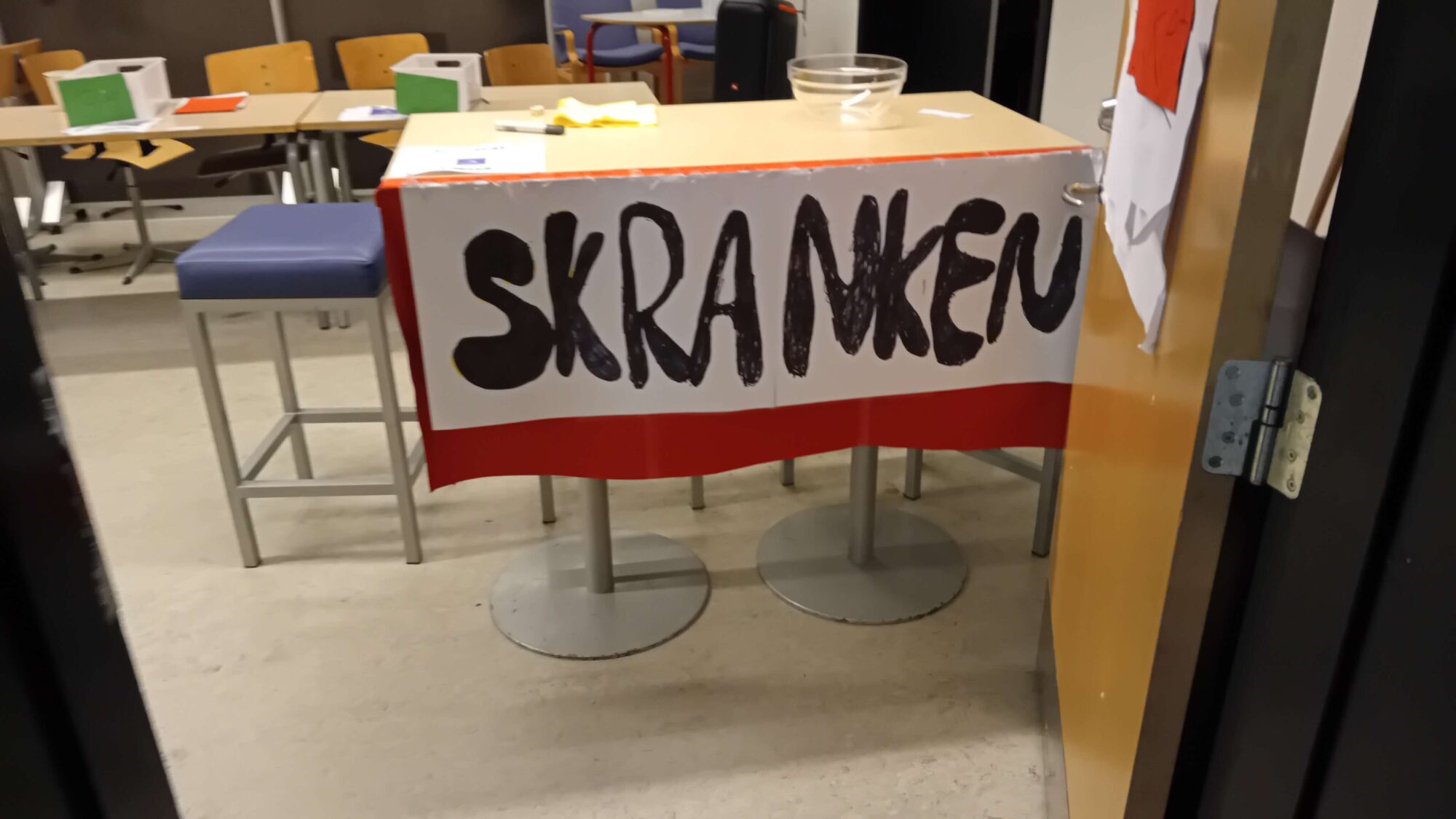 Et bord med et håndskrevet skilt, hvor der står SKRANKEN.