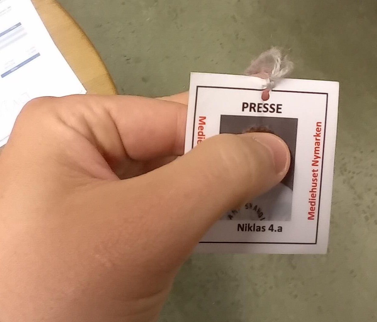 Pressekort fra Mediehuset Nymarken med foto, navn og klasse, holdt i en hånd.